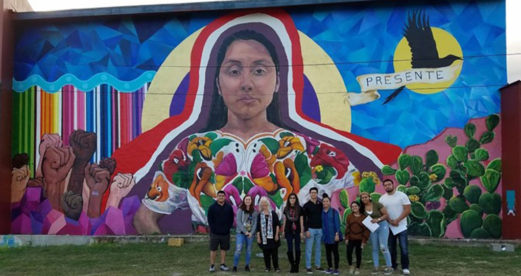 ECCL group of faculty and staff standing in front of a cultural mural in San Antonio.