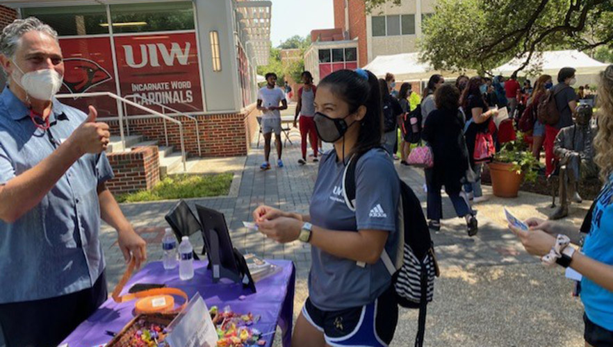 Students at a hand out table in the UIW quad