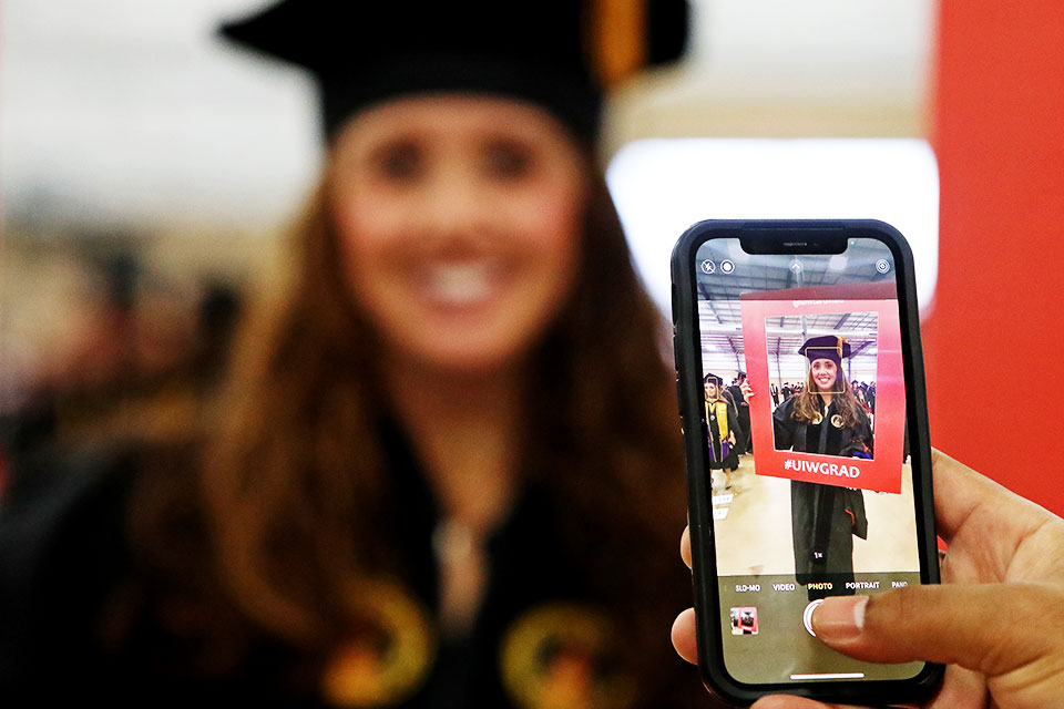 Photographer taking photo with iPhone of student graduating